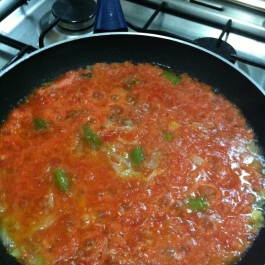 Sartén donde se está sofriendo tomate, cebolla y pimiento.